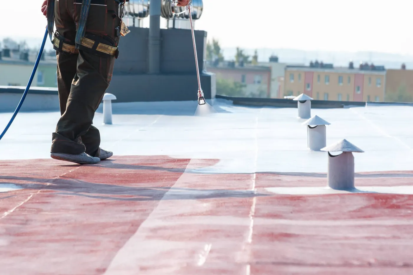 Liquid waterproofing being spray applied over an existing flat roof